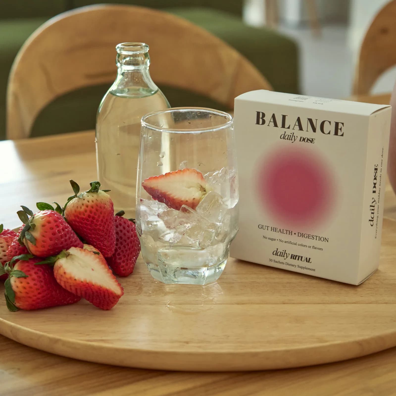 A box of BALANCE Daily Dose beside a glass of water and fresh strawberries